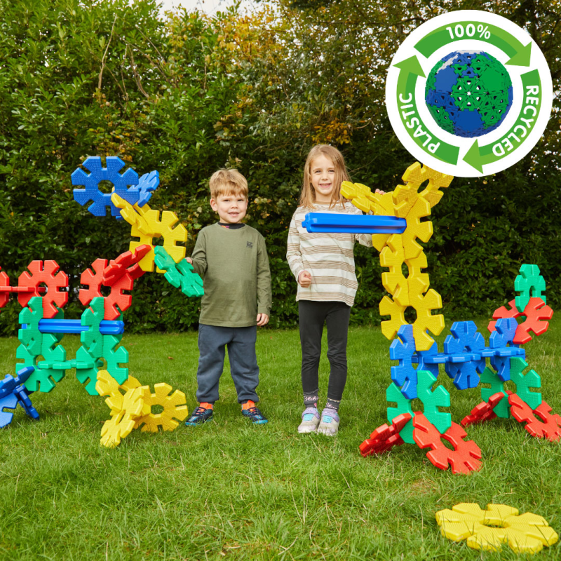 Kinder bauen gemeinsam mit bunten Giant Octoplay-Scheiben und -Stäben auf einer Rasenfläche während ihres Urlaubs
